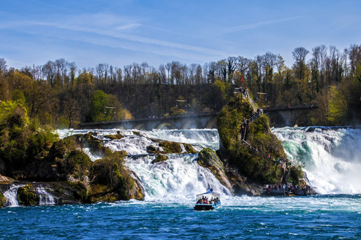 Tourists exploring Switzerland’s Rhine Falls by boat on a summer adventure with Ethiopian Airlines.