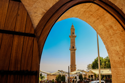 Historic Turkish minaret seen through a stone archway, offering an autumn cultural journey with Ethiopian Airlines.